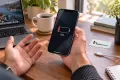 iPhone 12 Pro ile düşük şarj seviyesini fark eden müşteri; Teknonand logolu masa
